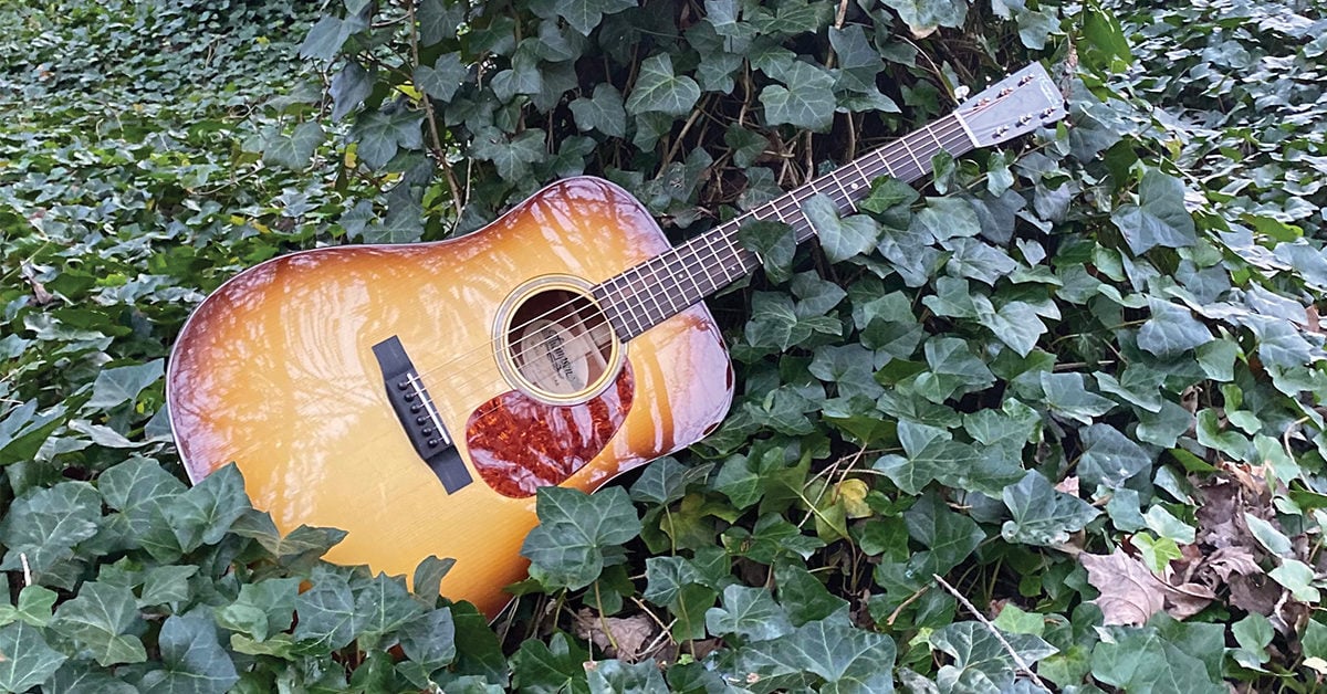 A Preston Thompson guitar lying in a bed a plants