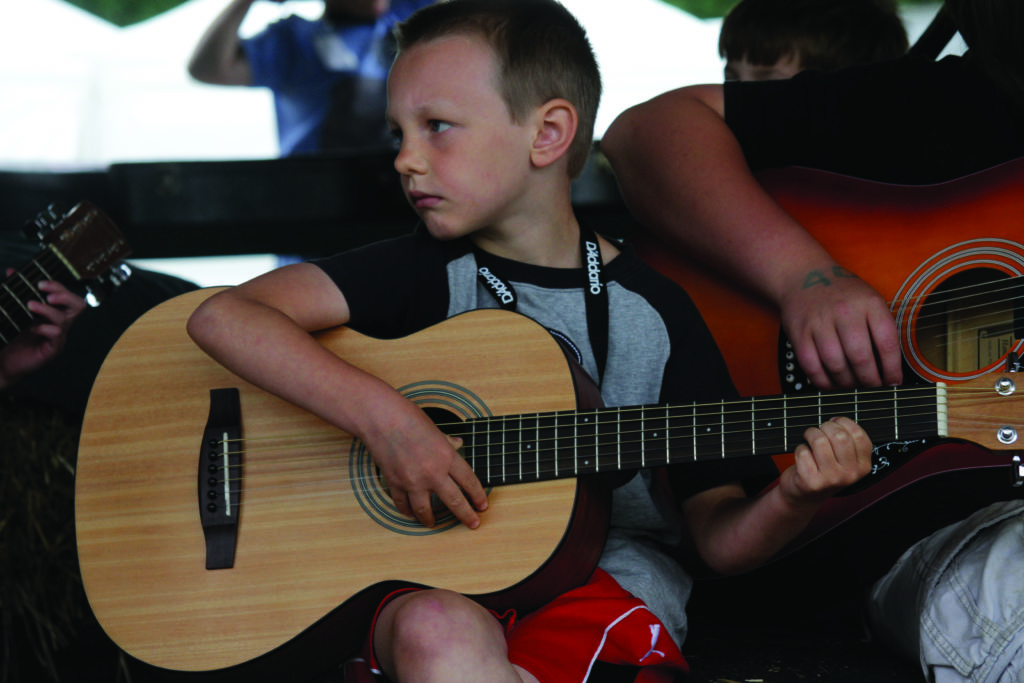 Child learning how to play the guitar at camp