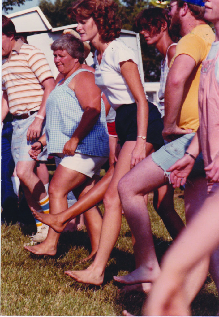 People dancing outside at a concert in shorts, t-shirts, and no shoes