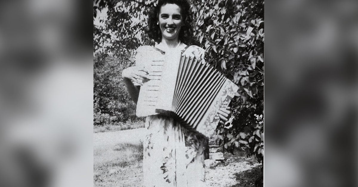 Black and white image of Sally smiling and playing her instrument