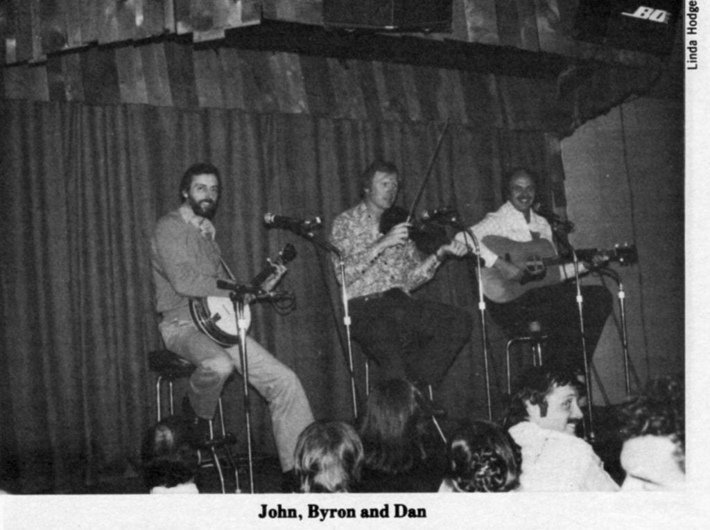 John, Byron, and Dan singing and playing instruments on stage.